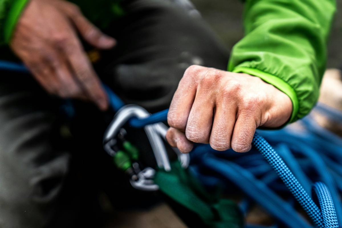 Climber testing Safety Alert Systems with gloves on vertical rock face