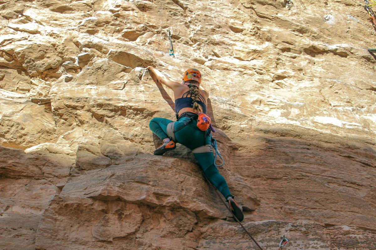 Close-up of worn climbing gloves gripping rough rock face during solo ascent—climbs alone with climbing gloves